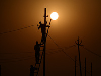 An electrician adjusts cables set up temporarily on the banks of the Sangam area in Prayagraj, India, on November 9, 2024, ahead of the upco...