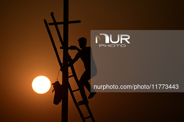 An electrician adjusts cables set up temporarily on the banks of the Sangam area in Prayagraj, India, on November 9, 2024, ahead of the upco...