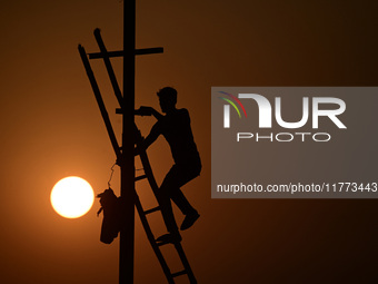 An electrician adjusts cables set up temporarily on the banks of the Sangam area in Prayagraj, India, on November 9, 2024, ahead of the upco...