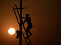 An electrician adjusts cables set up temporarily on the banks of the Sangam area in Prayagraj, India, on November 9, 2024, ahead of the upco...