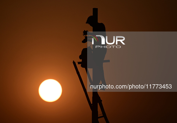 An electrician adjusts cables set up temporarily on the banks of the Sangam area in Prayagraj, India, on November 9, 2024, ahead of the upco...