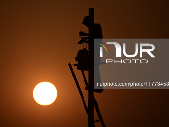 An electrician adjusts cables set up temporarily on the banks of the Sangam area in Prayagraj, India, on November 9, 2024, ahead of the upco...