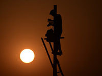 An electrician adjusts cables set up temporarily on the banks of the Sangam area in Prayagraj, India, on November 9, 2024, ahead of the upco...