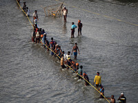 Labourers build a floating pontoon bridge across the river Ganges for devotees ahead of the upcoming Maha Kumbh 2025 festival in Prayagraj,...