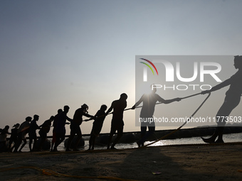 Labourers build a floating pontoon bridge across the river Ganges for devotees ahead of the upcoming Maha Kumbh 2025 festival in Prayagraj,...