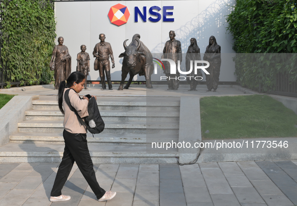 A woman walks past a bull of the National Stock Exchange (NSE) in the business district of Mumbai, India, on November 13, 2024. 