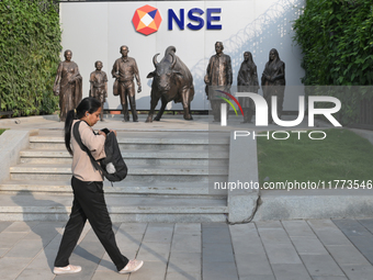 A woman walks past a bull of the National Stock Exchange (NSE) in the business district of Mumbai, India, on November 13, 2024. (