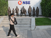 A woman walks past a bull of the National Stock Exchange (NSE) in the business district of Mumbai, India, on November 13, 2024. (