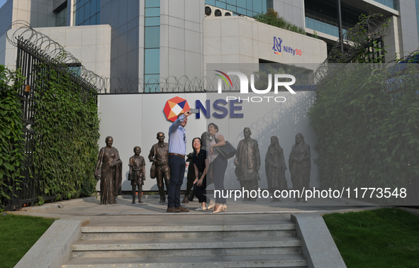 People take a selfie in front of a bull at the National Stock Exchange (NSE) in the business district of Mumbai, India, on November 13, 2024...