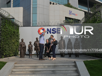 People take a selfie in front of a bull at the National Stock Exchange (NSE) in the business district of Mumbai, India, on November 13, 2024...