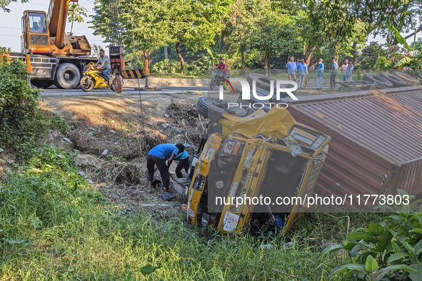 A crane lifts the wrecked accident-covered van beside a highway in Feni, Bangladesh, on November 13, 2024. 