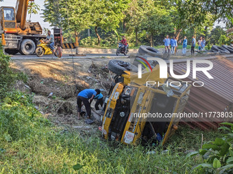 A crane lifts the wrecked accident-covered van beside a highway in Feni, Bangladesh, on November 13, 2024. (