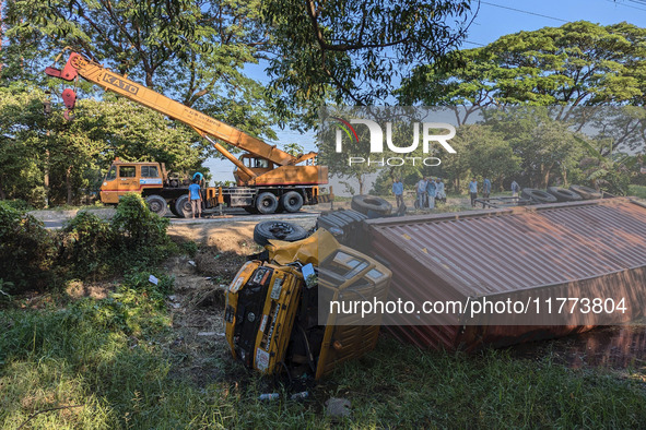 A crane lifts the wrecked accident-covered van beside a highway in Feni, Bangladesh, on November 13, 2024. 