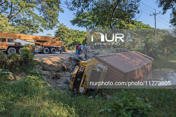 A crane lifts the wrecked accident-covered van beside a highway in Feni, Bangladesh, on November 13, 2024. 