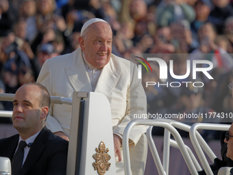 Pope Francis greets the crowd as he arrives for his weekly General Audience in Saint Peter's Square, Vatican City, on November 13, 2024. (