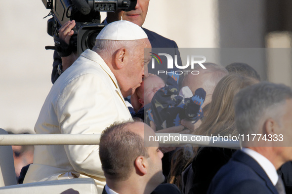 Pope Francis kisses a child when he arrives for his weekly general audience in Vatican City, Vatican, on November 13, 2024. 