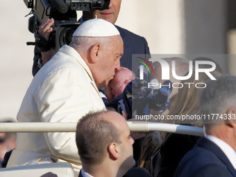 Pope Francis kisses a child when he arrives for his weekly general audience in Vatican City, Vatican, on November 13, 2024. (