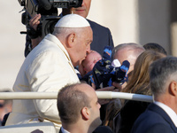 Pope Francis kisses a child when he arrives for his weekly general audience in Vatican City, Vatican, on November 13, 2024. (