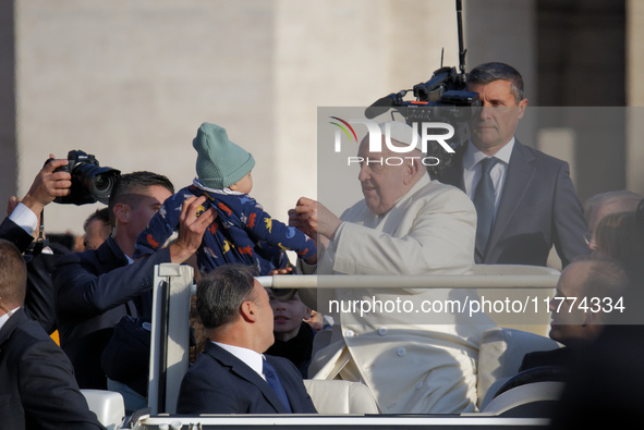 Pope Francis gives a candy to a child when he arrives for his weekly general audience in Vatican City, Vatican, on November 13, 2024. 