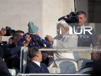 Pope Francis gives a candy to a child when he arrives for his weekly general audience in Vatican City, Vatican, on November 13, 2024. (