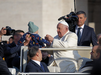 Pope Francis gives a candy to a child when he arrives for his weekly general audience in Vatican City, Vatican, on November 13, 2024. (