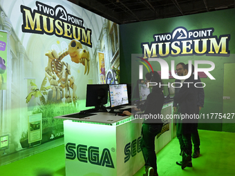 Visitors and gamers play the game ''Two Point Museum,'' developed by Two Point Studios and edited by Sega, at the ''Paris Games Week'' video...