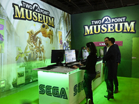 Visitors and gamers play the game ''Two Point Museum,'' developed by Two Point Studios and edited by Sega, at the ''Paris Games Week'' video...