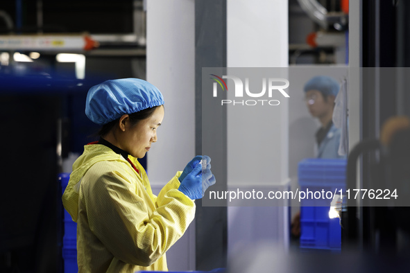 A worker produces new materials for high-end special-shaped anti-counterfeiting bottle caps at a workshop in the Sihong Economic Development...