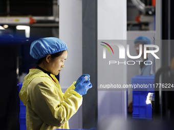 A worker produces new materials for high-end special-shaped anti-counterfeiting bottle caps at a workshop in the Sihong Economic Development...