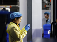 A worker produces new materials for high-end special-shaped anti-counterfeiting bottle caps at a workshop in the Sihong Economic Development...