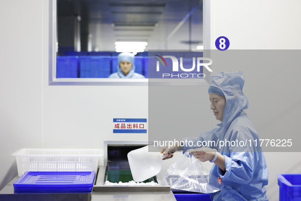 A worker produces new materials for high-end special-shaped anti-counterfeiting bottle caps at a workshop in the Sihong Economic Development...