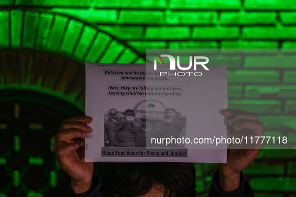 A member of the 'Save Youth Save Future' Foundation holds a candle and placard during a candlelight vigil against the recent grenade blast a...