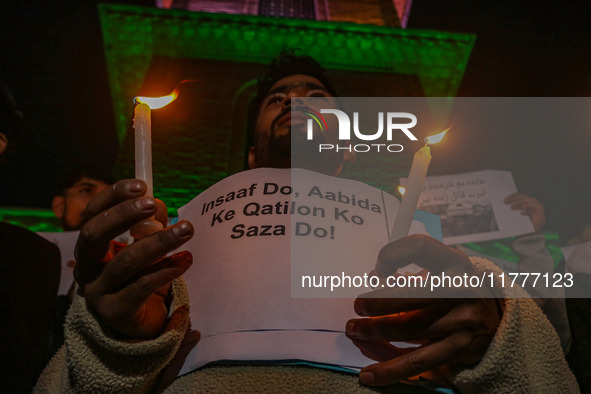 A member of the 'Save Youth Save Future' Foundation holds a candle and placard during a candlelight vigil against the recent grenade blast a...