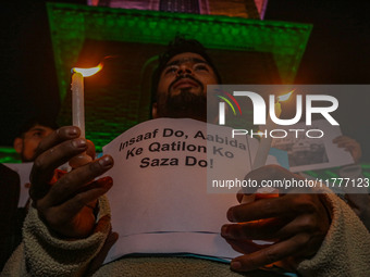 A member of the 'Save Youth Save Future' Foundation holds a candle and placard during a candlelight vigil against the recent grenade blast a...