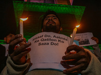 A member of the 'Save Youth Save Future' Foundation holds a candle and placard during a candlelight vigil against the recent grenade blast a...