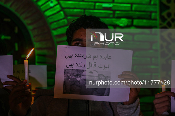 A member of the 'Save Youth Save Future' Foundation holds a candle and placard during a candlelight vigil against the recent grenade blast a...