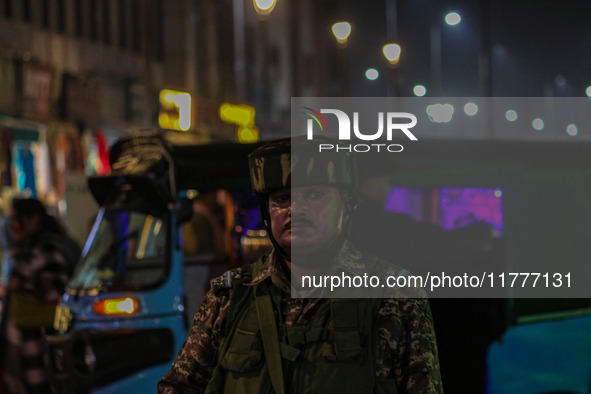 An Indian security personnel stands guard during a candlelight vigil against the recent grenade blast at a Sunday market in Srinagar, Jammu...