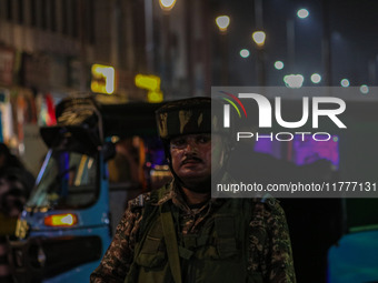 An Indian security personnel stands guard during a candlelight vigil against the recent grenade blast at a Sunday market in Srinagar, Jammu...