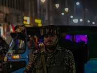 An Indian security personnel stands guard during a candlelight vigil against the recent grenade blast at a Sunday market in Srinagar, Jammu...