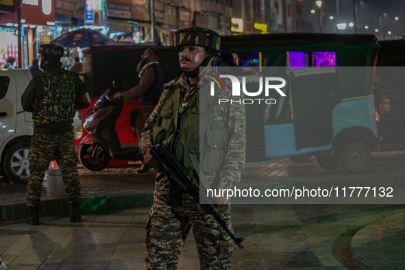 An Indian security personnel stands guard during a candlelight vigil against the recent grenade blast at a Sunday market in Srinagar, Jammu...