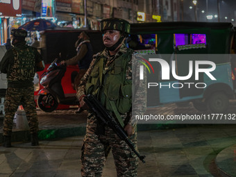 An Indian security personnel stands guard during a candlelight vigil against the recent grenade blast at a Sunday market in Srinagar, Jammu...