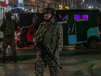 An Indian security personnel stands guard during a candlelight vigil against the recent grenade blast at a Sunday market in Srinagar, Jammu...