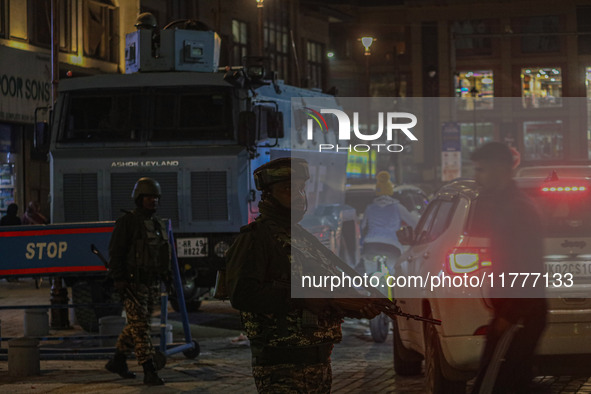 An Indian security personnel stands guard during a candlelight vigil against the recent grenade blast at a Sunday market in Srinagar, Jammu...