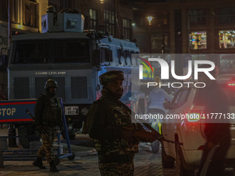 An Indian security personnel stands guard during a candlelight vigil against the recent grenade blast at a Sunday market in Srinagar, Jammu...