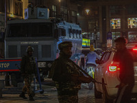 An Indian security personnel stands guard during a candlelight vigil against the recent grenade blast at a Sunday market in Srinagar, Jammu...