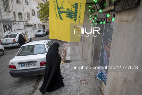 A veiled Iranian woman walks under a flag of Lebanon's Hezbollah while arriving to take part in a charity ceremony for donating gold and mon...