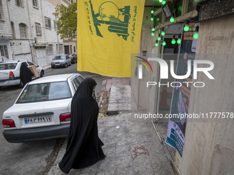 A veiled Iranian woman walks under a flag of Lebanon's Hezbollah while arriving to take part in a charity ceremony for donating gold and mon...