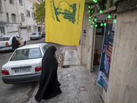 A veiled Iranian woman walks under a flag of Lebanon's Hezbollah while arriving to take part in a charity ceremony for donating gold and mon...