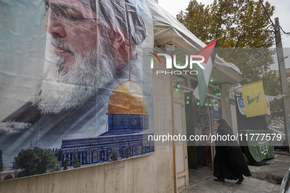 A veiled Iranian woman walks under Lebanon's Hezbollah and Palestine flags while arriving to take part in a charity ceremony for donating go...