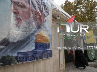 A veiled Iranian woman walks under Lebanon's Hezbollah and Palestine flags while arriving to take part in a charity ceremony for donating go...